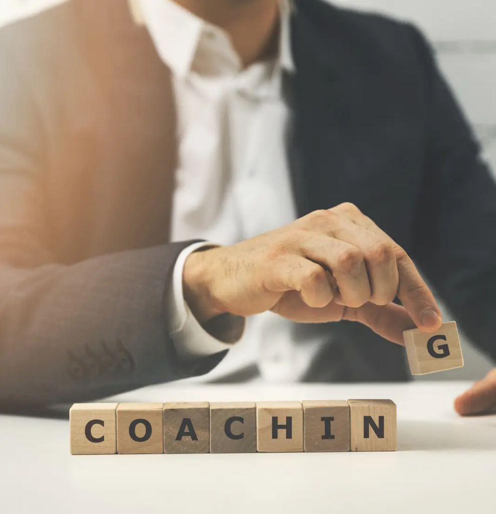 Successful business coach | hand holding wooden blocks that spell out "coaching"