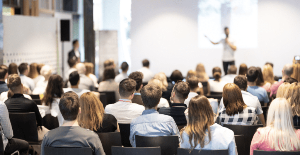 Starting a coaching business | Person delivering a seminar to a group of people. 