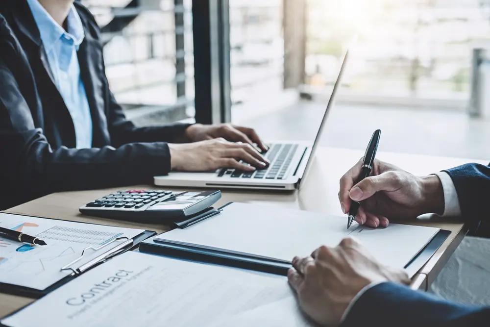 Franchise opportunities | People in a business meeting, wearing shirts and sitting at a desk with laptops.