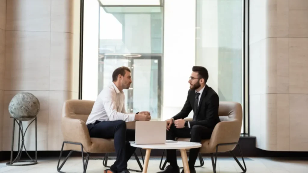 2 males sitting at a table chatting about starting a coaching business