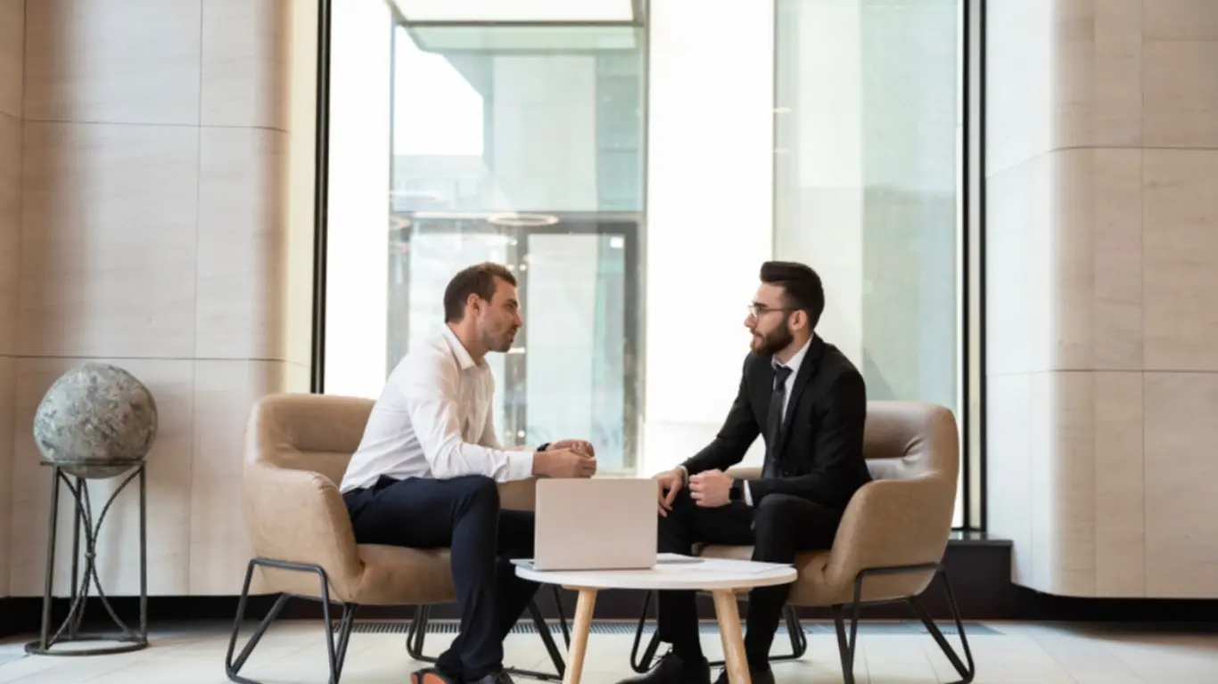 2 males sitting at a table chatting about starting a coaching business